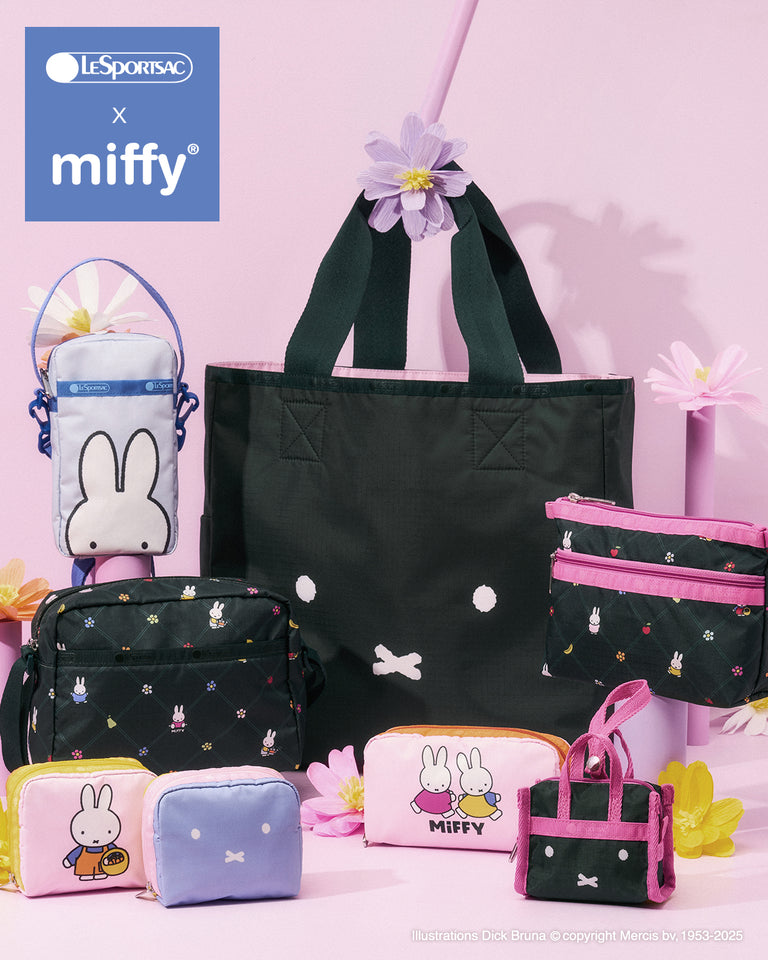 LeSportsac x Miffy collection arranged on a soft pink background with pastel flowers, featuring a large dark green tote with a minimalist Miffy face, assorted pouches and mini bags in pink, blue, and black with Miffy character and print details, and a blue-and-white crossbody bag, displayed on cylindrical pedestals with the LeSportsac x Miffy logo in the top left.